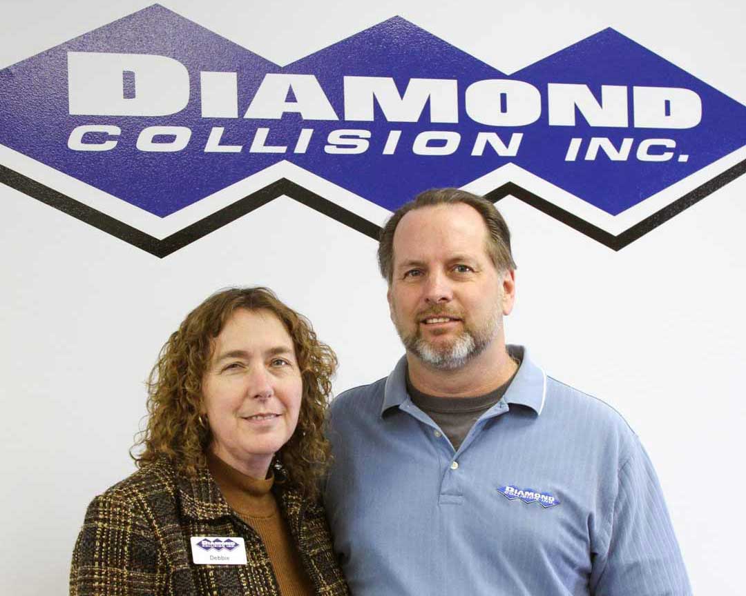 Debbie and Allen in front of a Diamond Collision Services Inc. logo.
