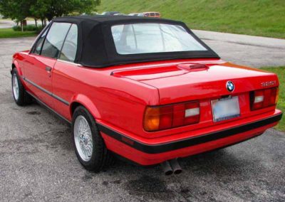 Red 1993 BMW 325i convertible E30 outside from the rear angle.