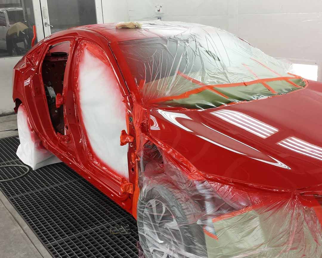 Car being repainted red during repairs.